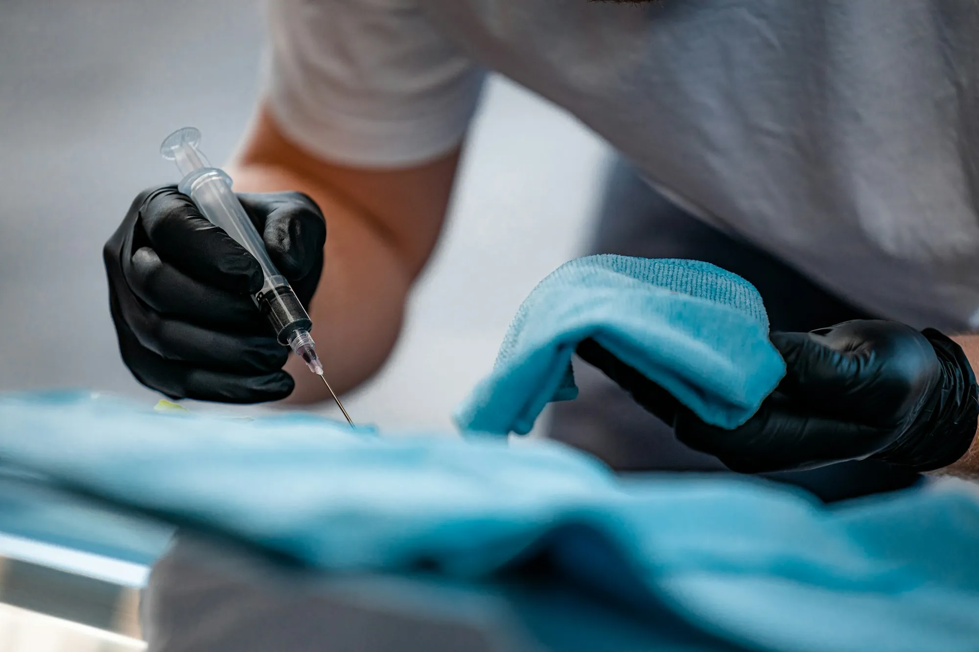 Hands in black gloves wiping a surface with a cloth
